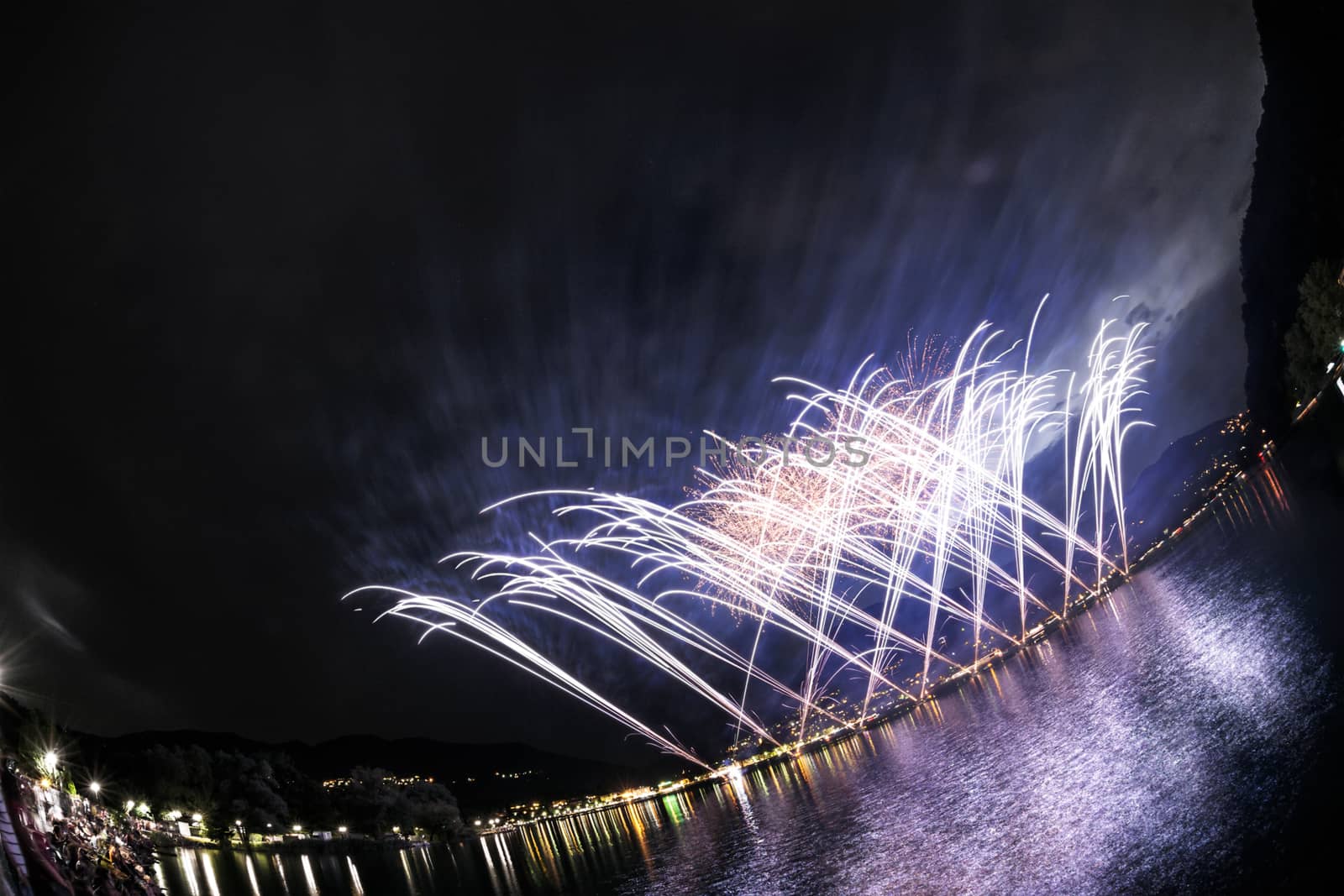 Fireworks on the Lugano Lake in a summer evening seen from lakefornt of Lavena-Ponte Tresa, Lombardy - Italy