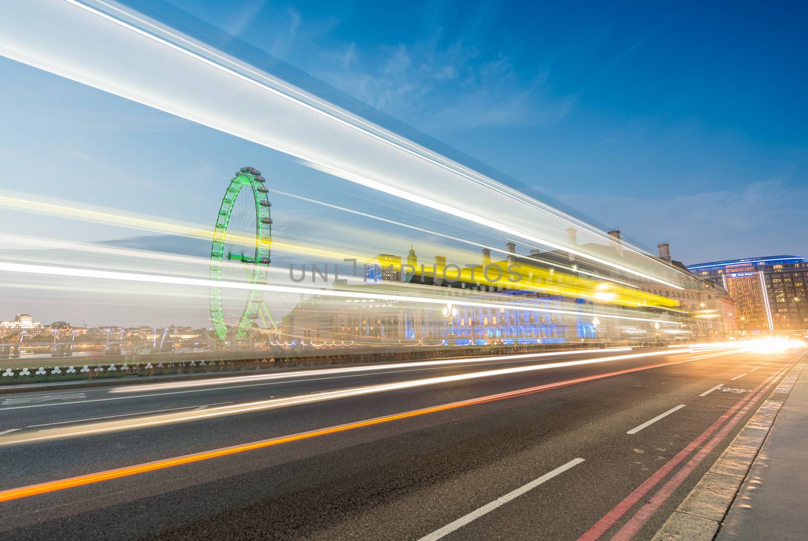 LONDON - JUNE 13, 2015: Light trails across Westminster Bridge with London Eye. London attracts 50 million people annually.