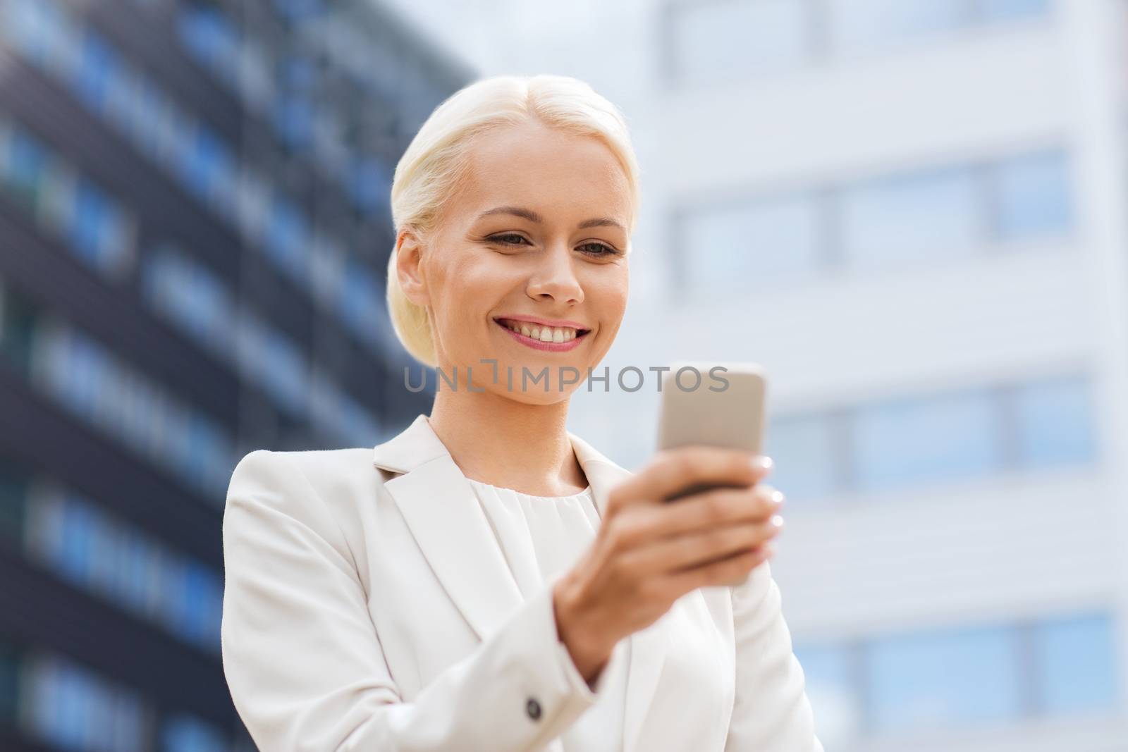 smiling businesswoman with smartphone outdoors by dolgachov