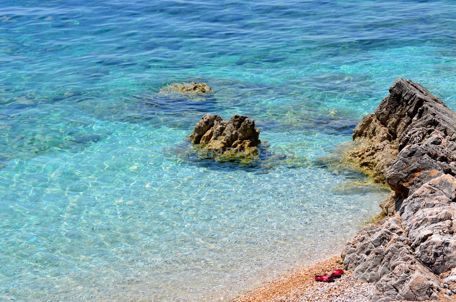 beach with clear water and red slippers