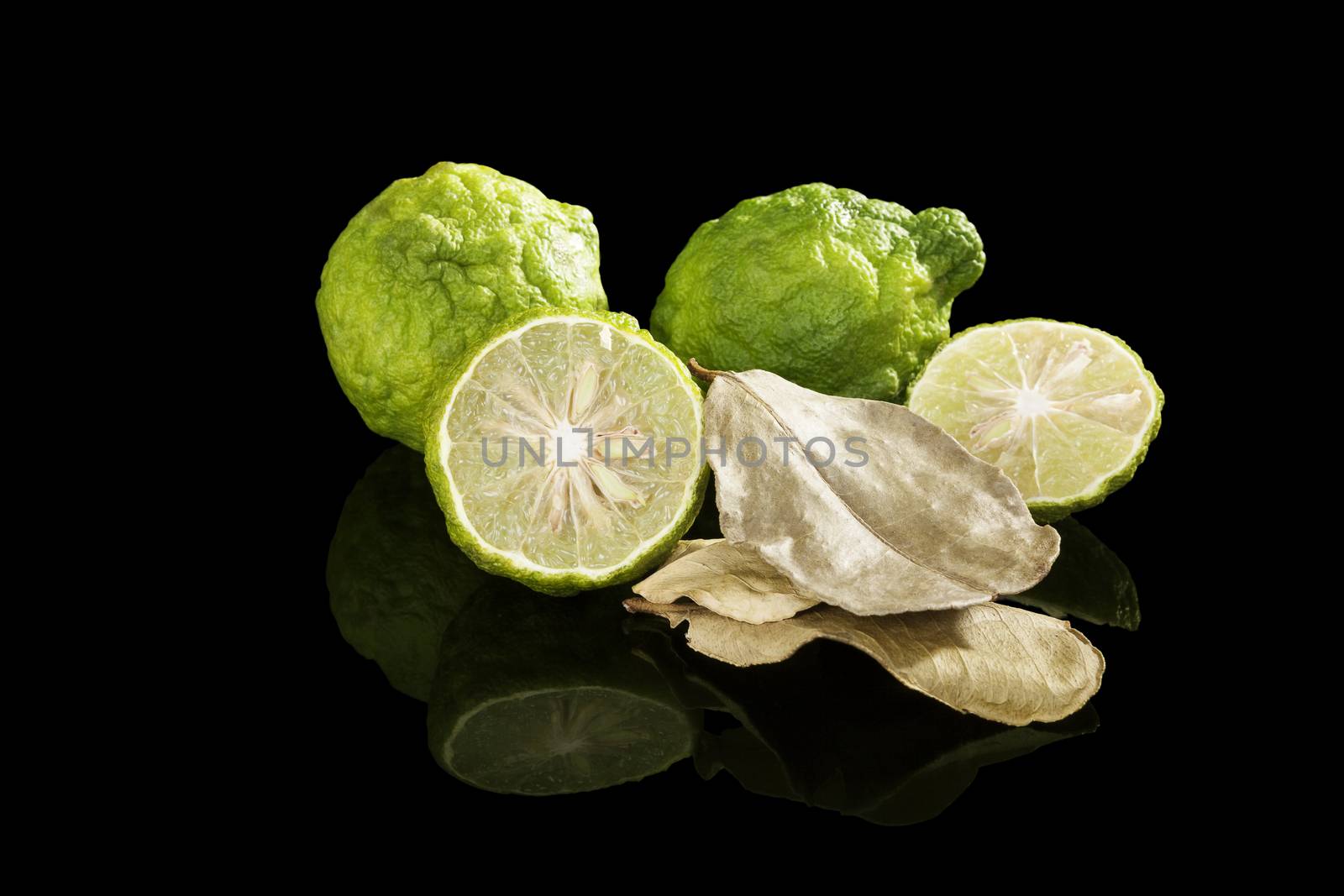 Dried bergamot leaves and fresh fruits isolated on black background. Culinary cooking, tropical fruit bergamot orange.