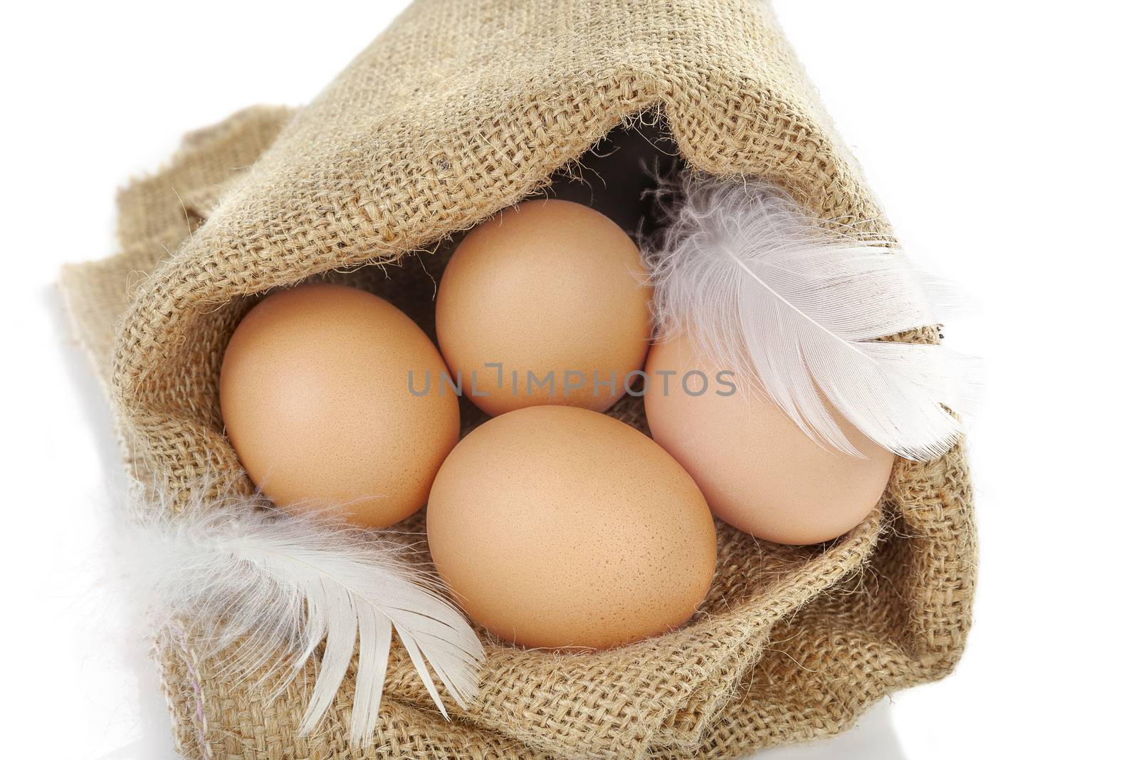 Brown eggs with feather in burlap bag isolated on white background, top view.