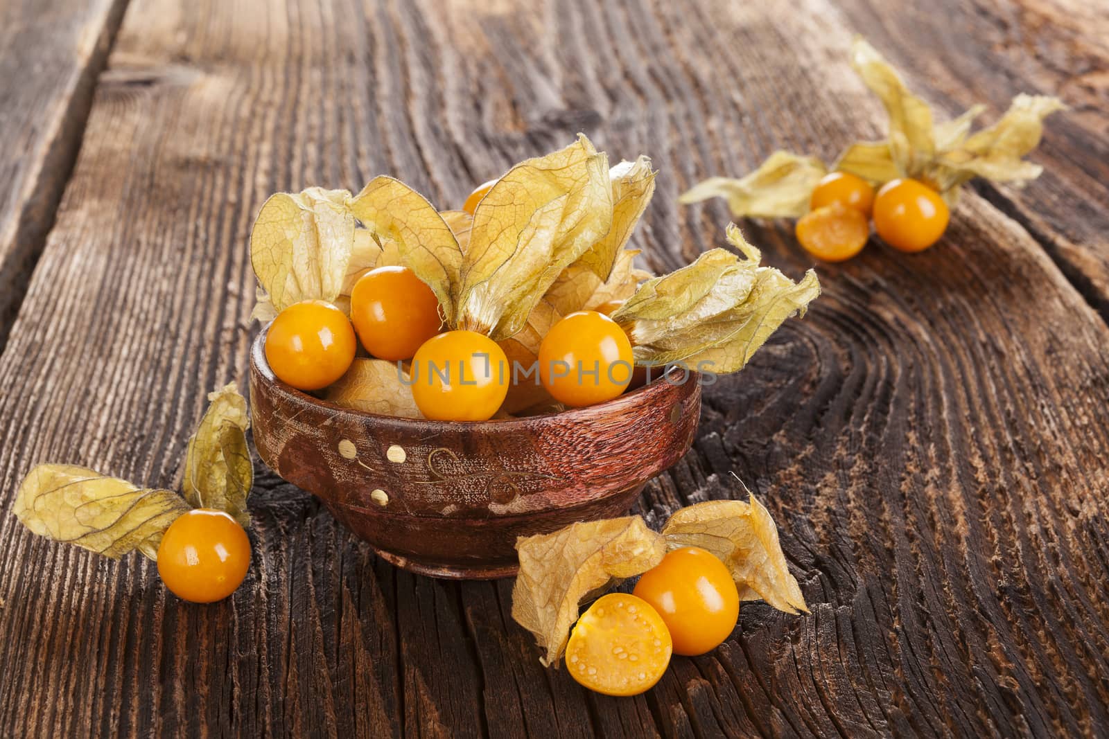 Physalis, groundcherries in bowl on brown textured aged background. Tropical healthy fruit eating.