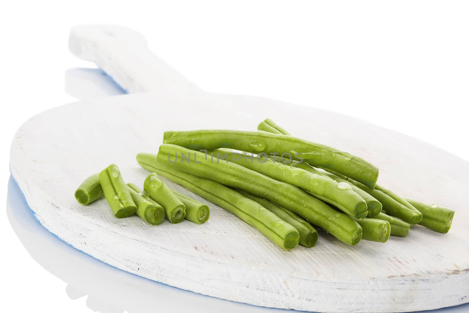 Green beans with water drops on wooden chopping board isolated on white background. Healthy eating. 