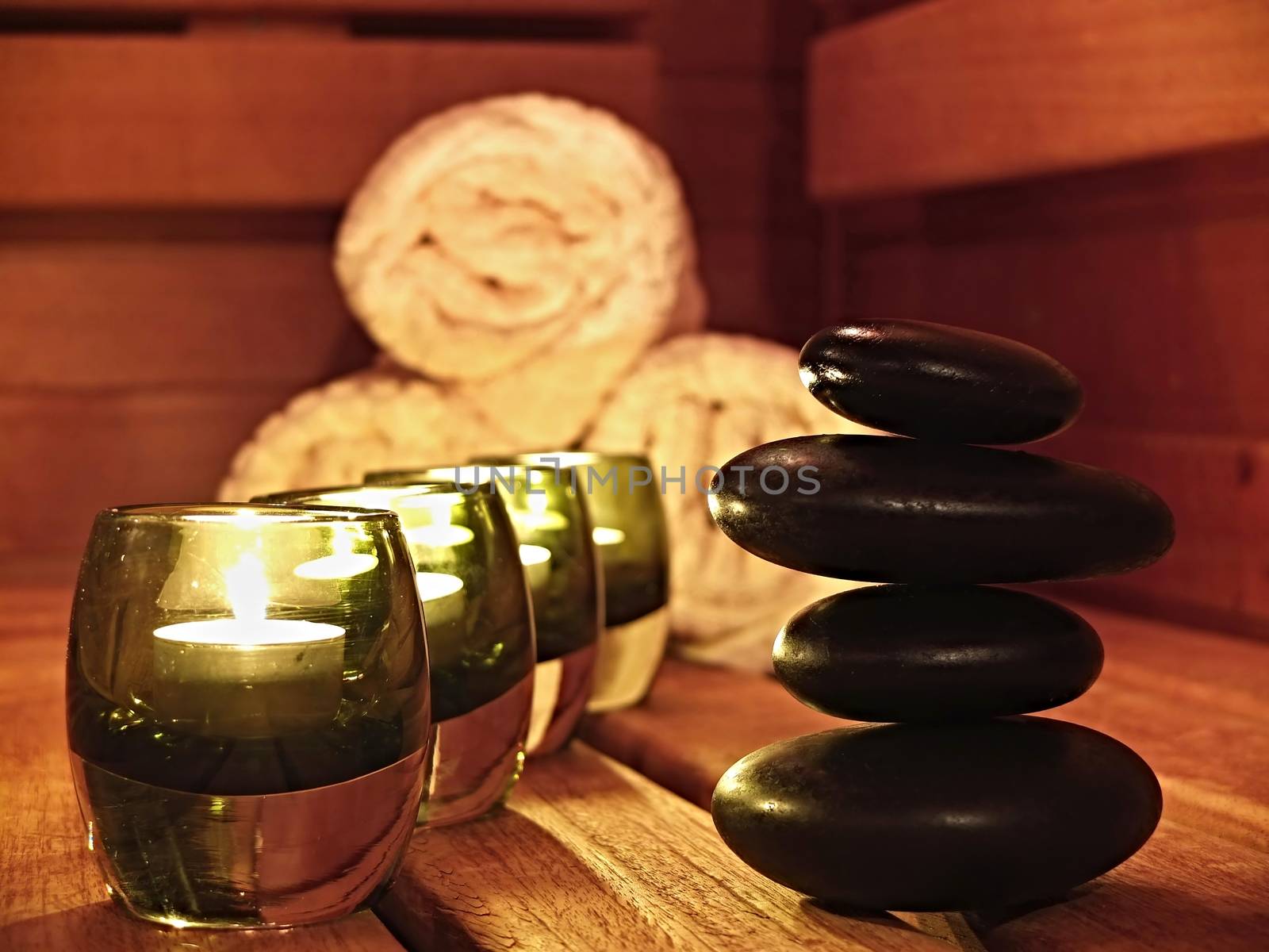 Spa composition of candles and black zen stones with towels in behind