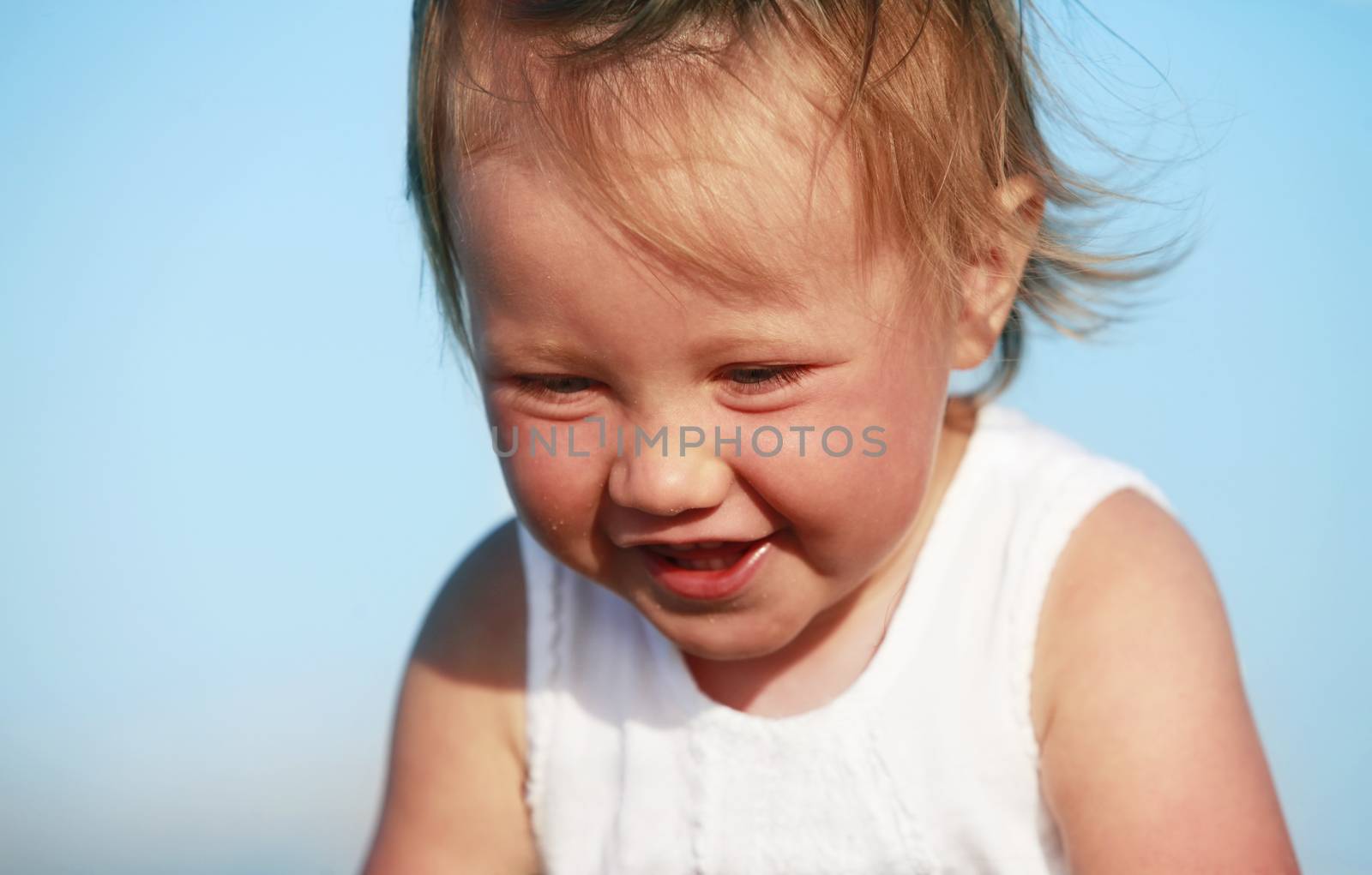 Little girl laughing in the background of blue sky