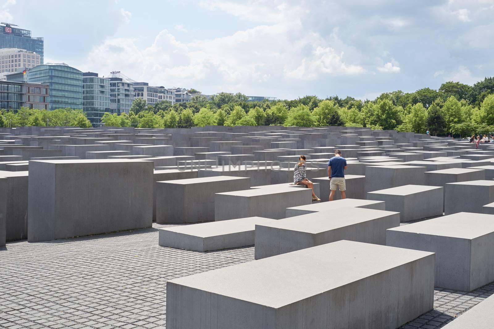 BERLIN, GERMANY - JULY 08: Young couple seated on stone block at the Memorial to the Murdered Jews of Europe. July 08, 2015 in Berlin.
