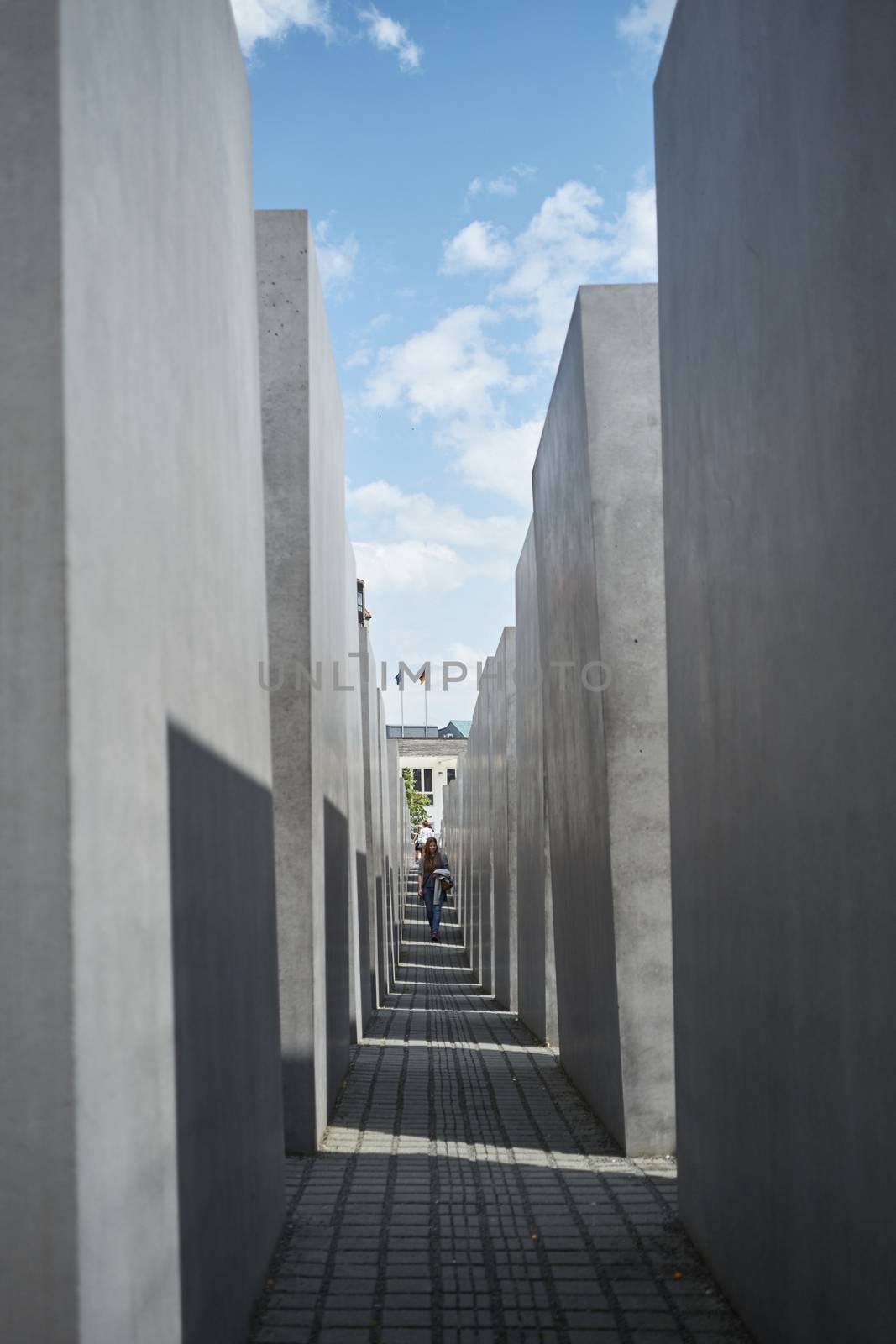 BERLIN, GERMANY - JULY 08: Tourists walking among stone blocks at the Memorial to the Murdered Jews of Europe. July 08, 2015 in Berlin.
