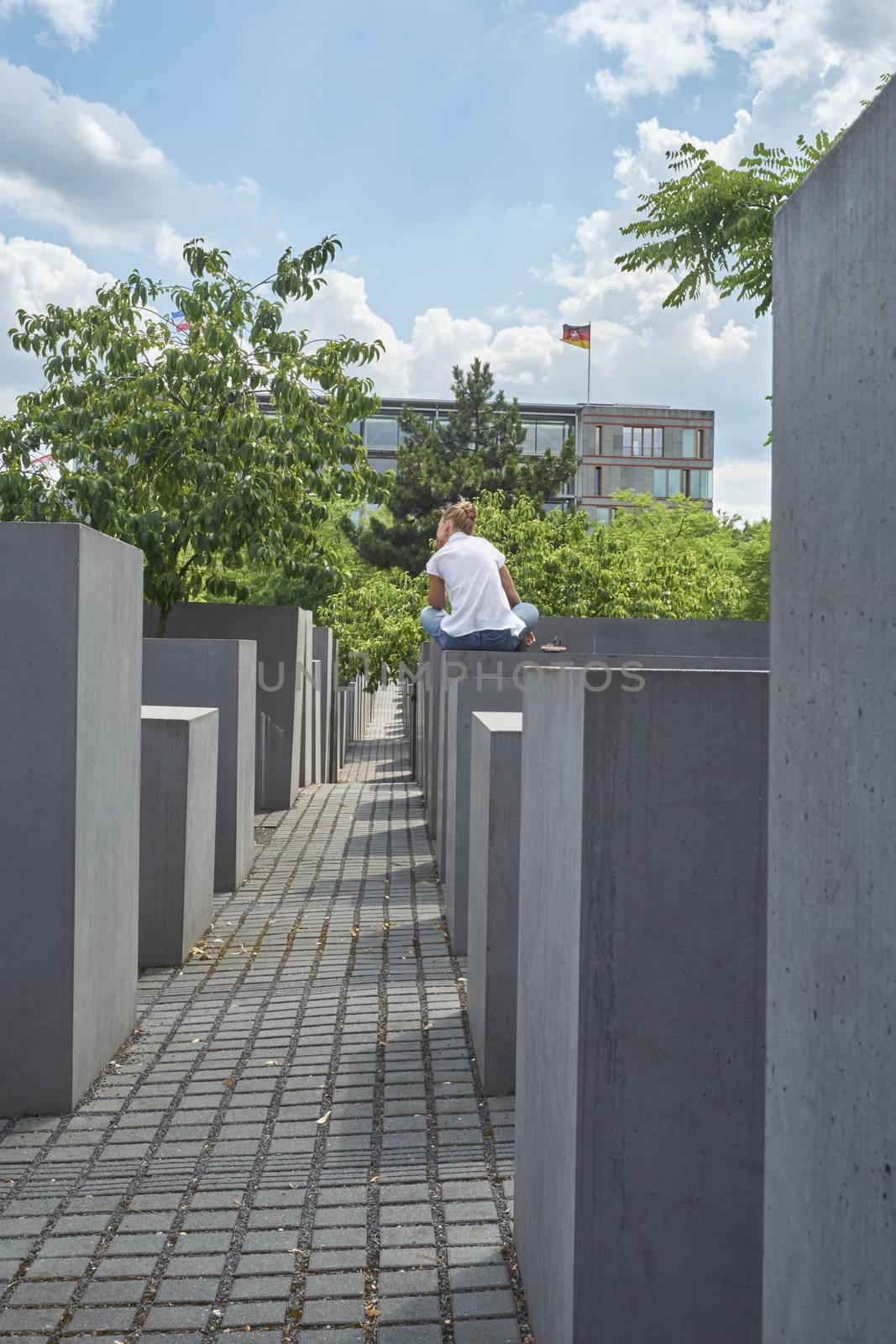 BERLIN, GERMANY - JULY 08: Young girl seated on stone block at the Memorial to the Murdered Jews of Europe. July 08, 2015 in Berlin.