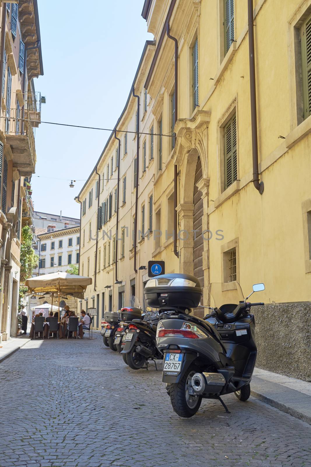 VERONA, ITALY - JULY 11: Low angle shot of stone street with scooters parked. July 11, 2015 in Verona.