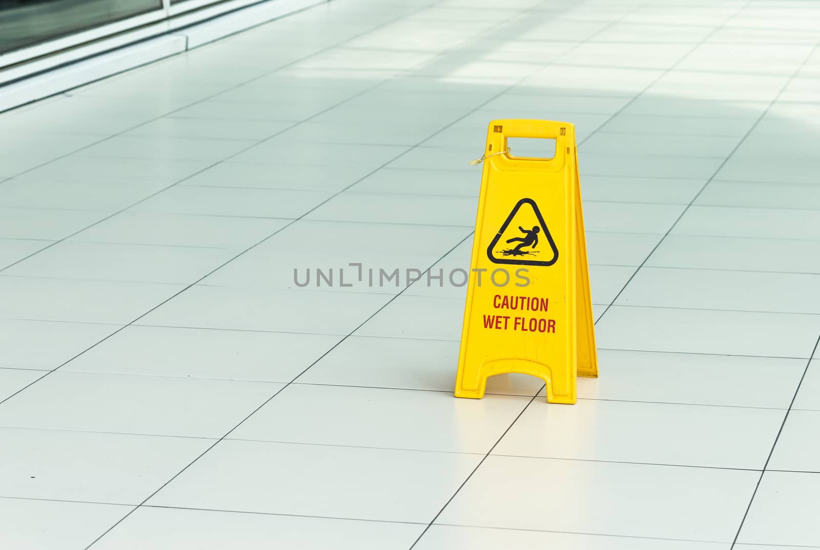 Yellow sign that alerts for wet floor in airport.