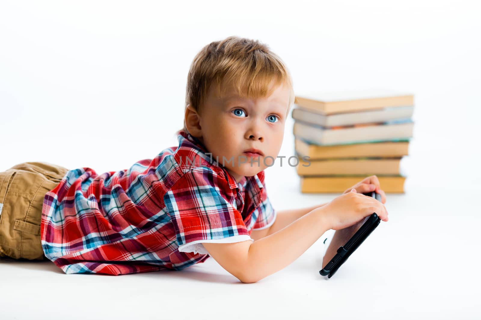 A small boy with tablet computer and books
