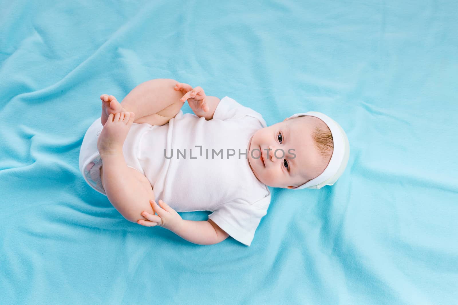 beautiful baby in the cap on a blue blanket