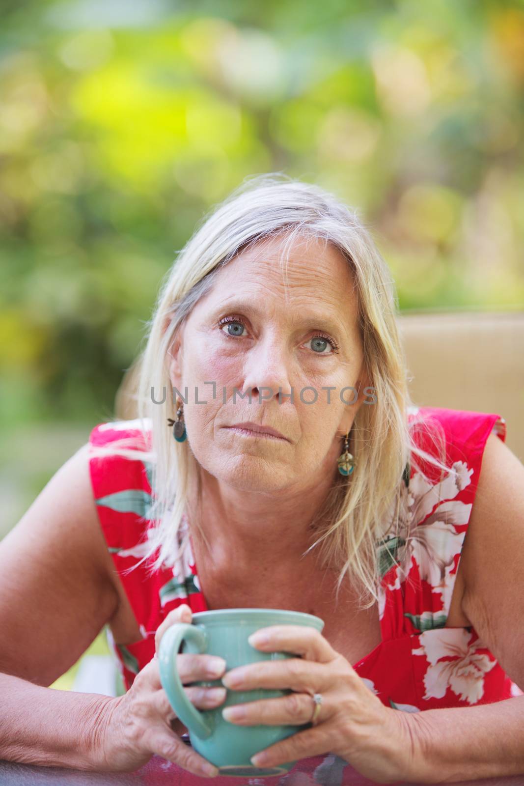 Sympathetic middle aged Caucasian female holding a coffee up