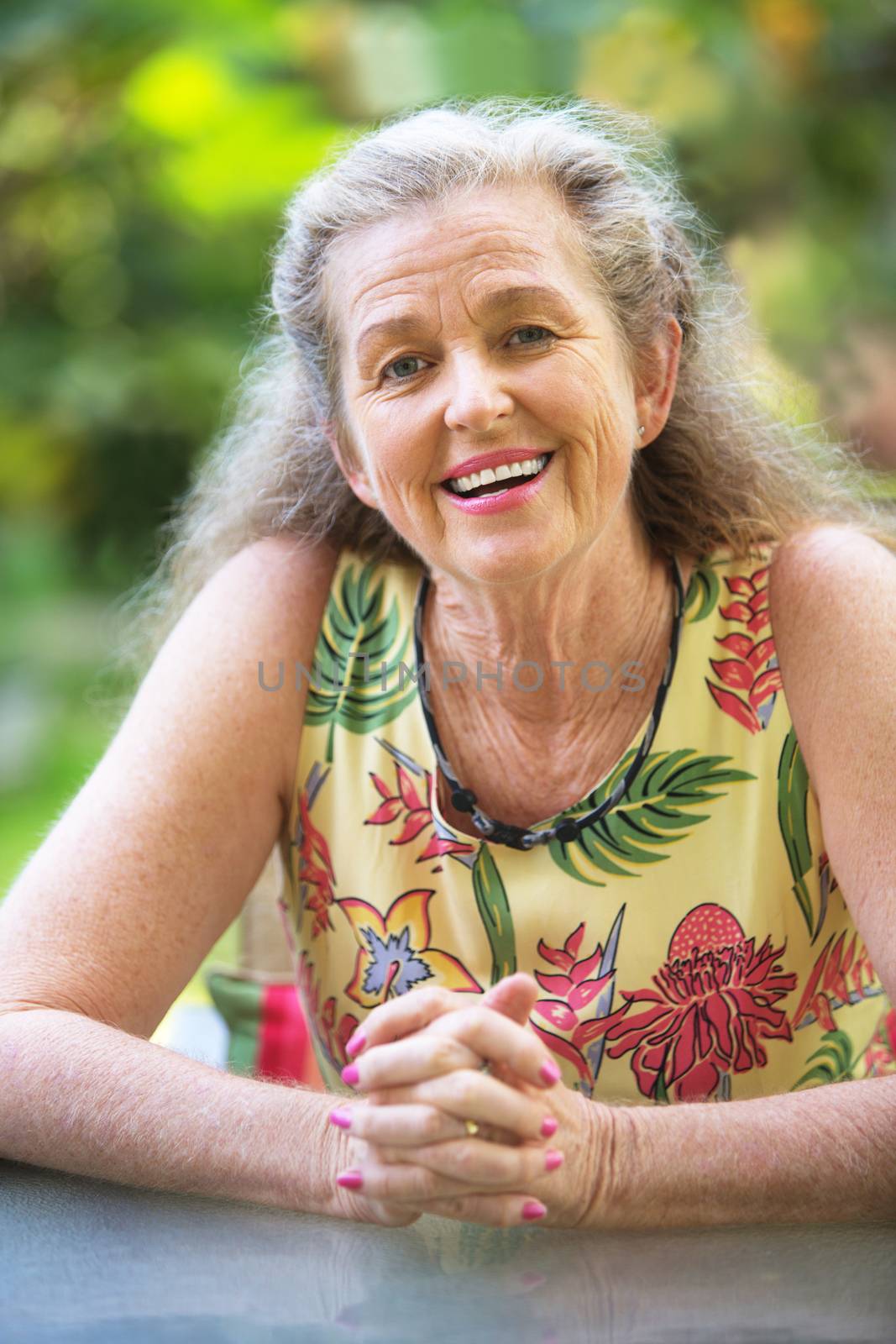 Smiling woman with gray hair and folded hands