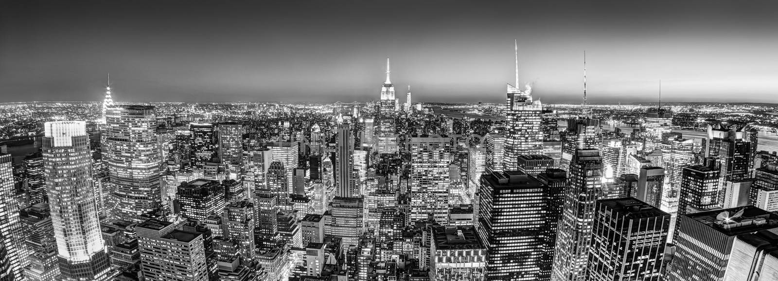 New York City. Manhattan downtown skyline with illuminated Empire State Building and skyscrapers at dusk seen from observation deck. Panoramic view. Black and white photo.