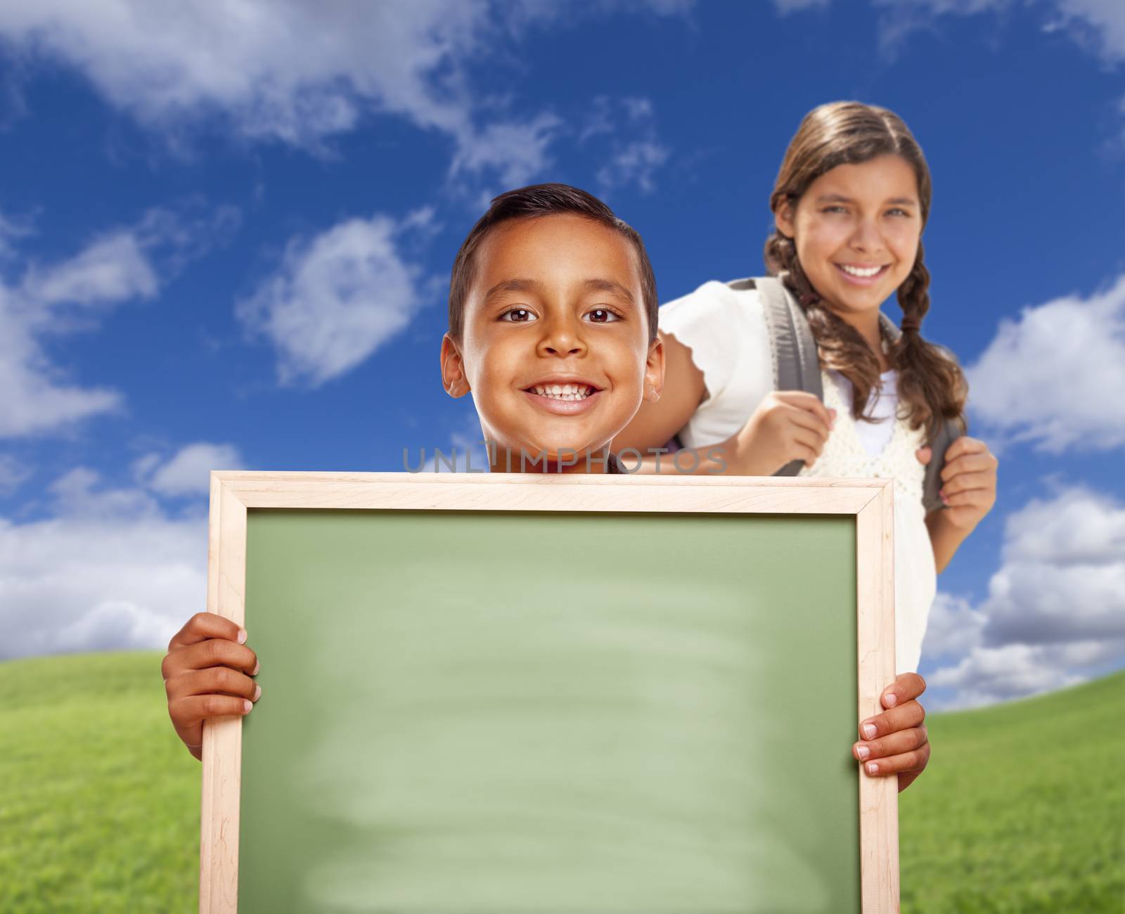 Hispanic Boy and Girl In Field Holding Blank Chalk Board by Feverpitched