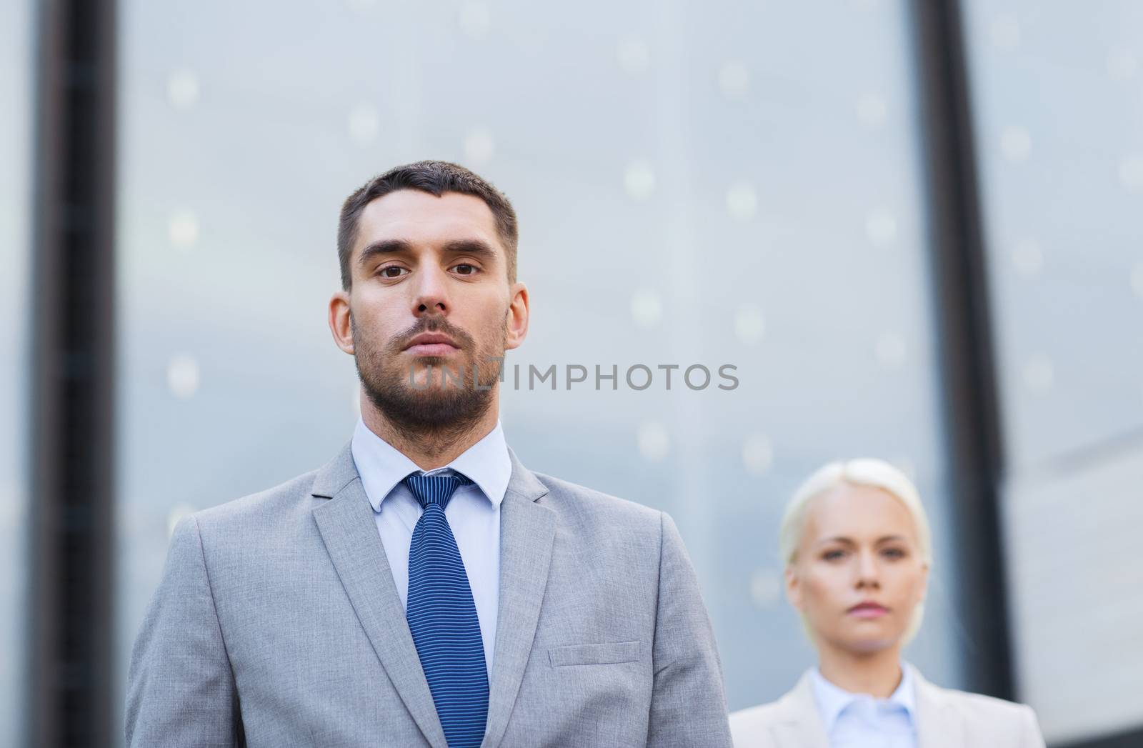 business, partnership, success and people concept - businessman and businesswoman standing over office building