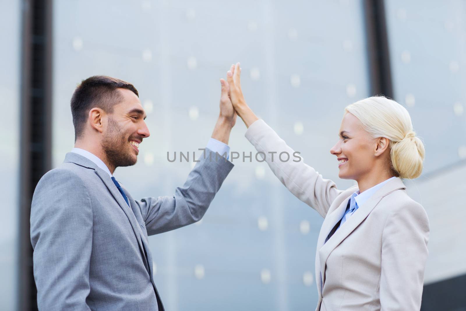 business, partnership, success, gesture and people concept - smiling businessman and businesswoman standing over office building