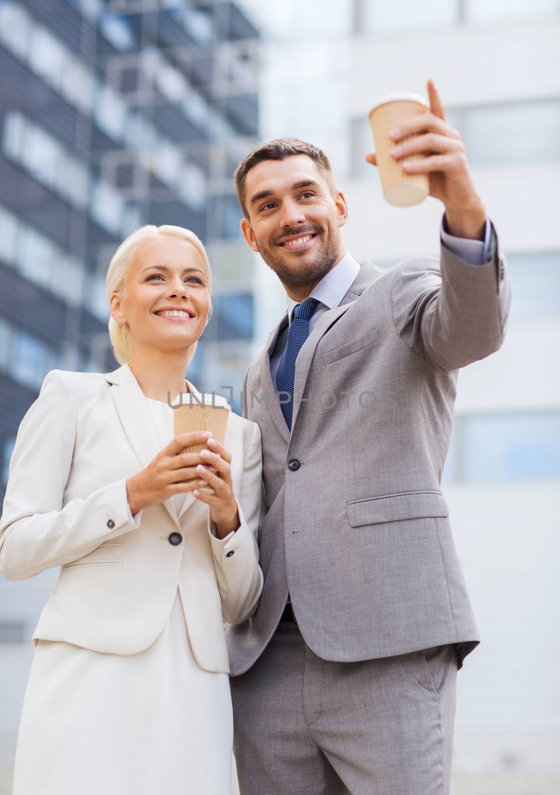 smiling businessmen with paper cups outdoors by dolgachov