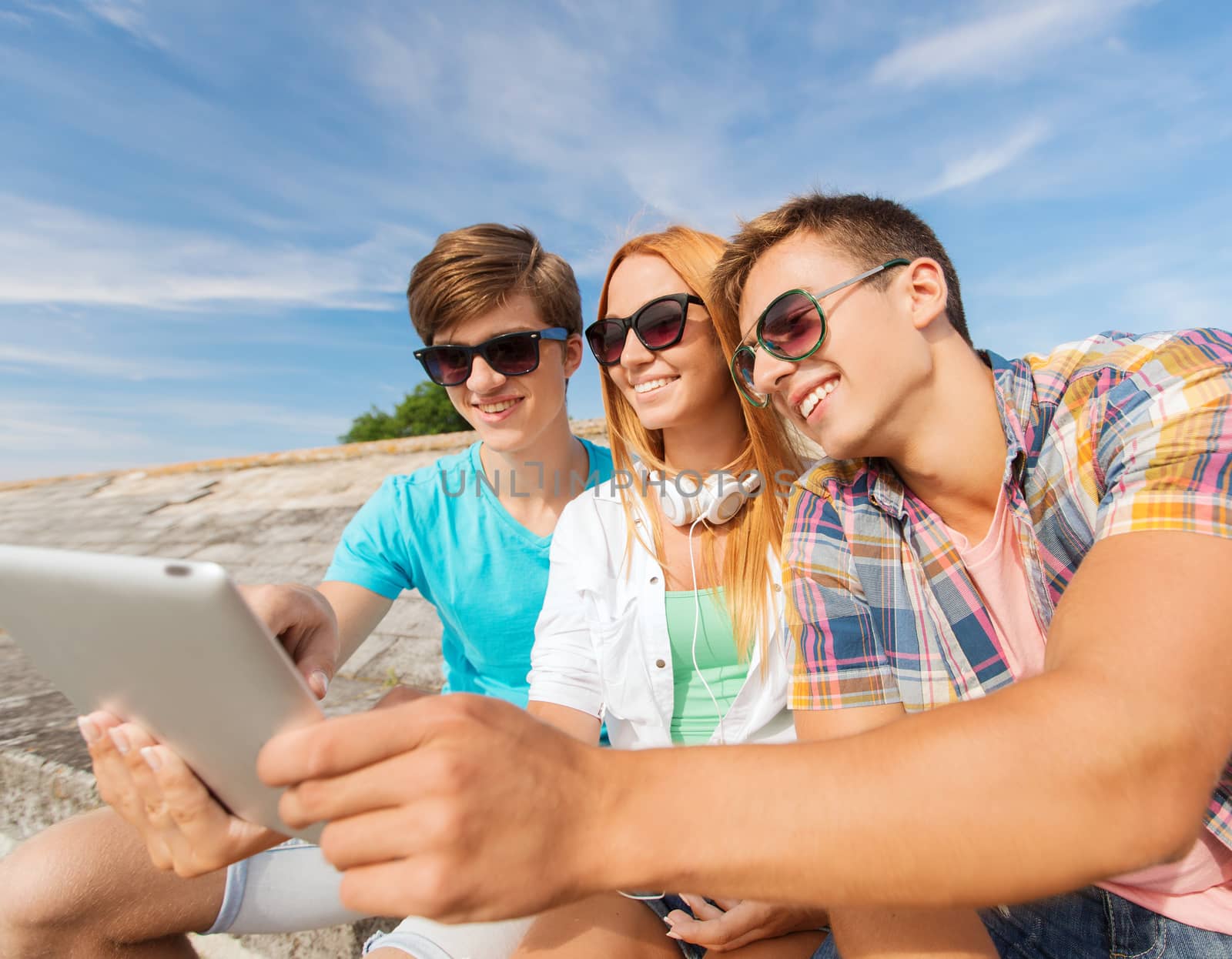 group of smiling friends with tablet pc outdoors by dolgachov