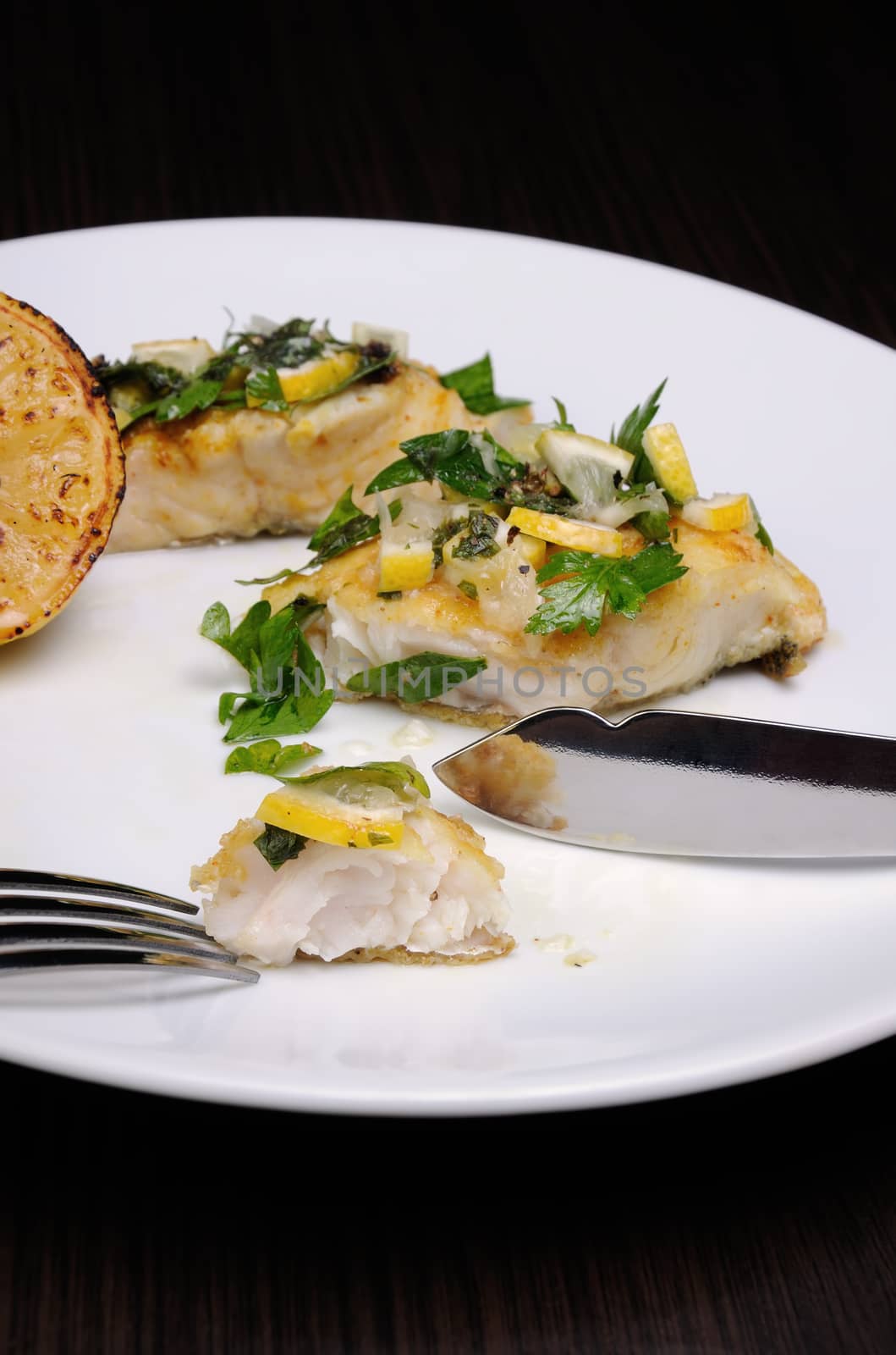 slice of baked fish perch with herbs and lemon slices