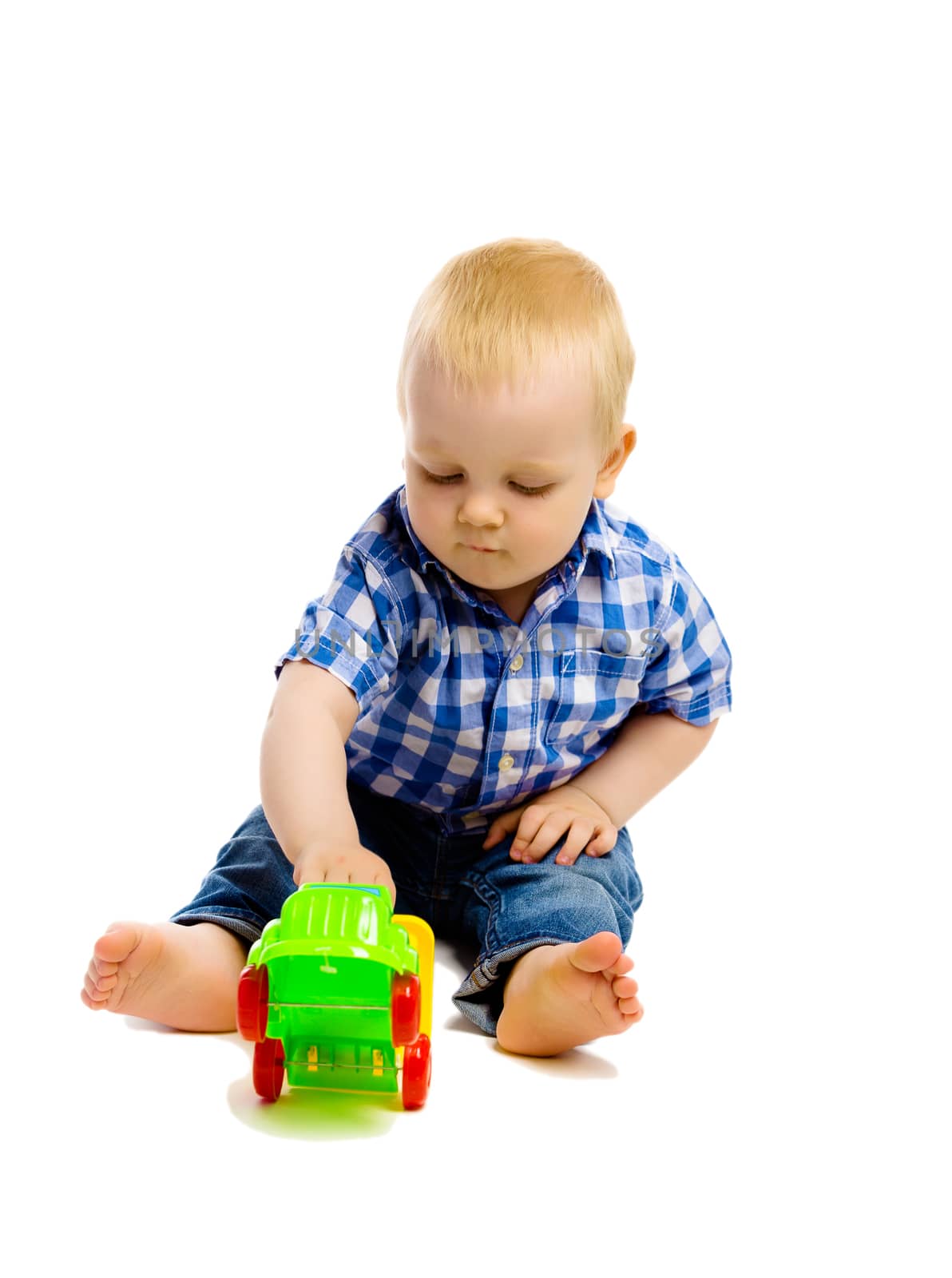 A little boy in a plaid shirt and jeans with toys on a white background