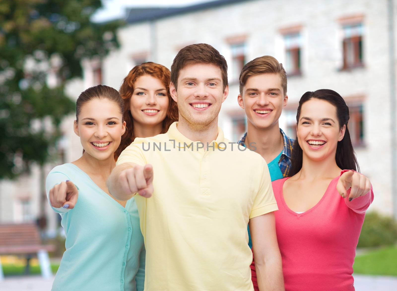 group of smiling teenagers over campus background by dolgachov