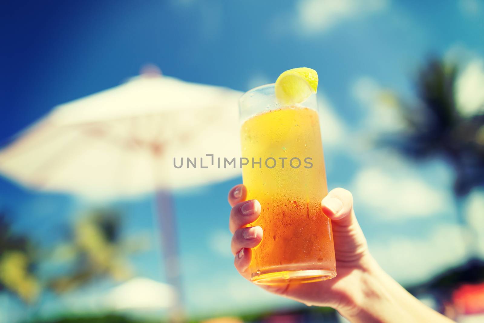 vacation, beverage and travel concept - close-up of female hand holding glass with cocktail
