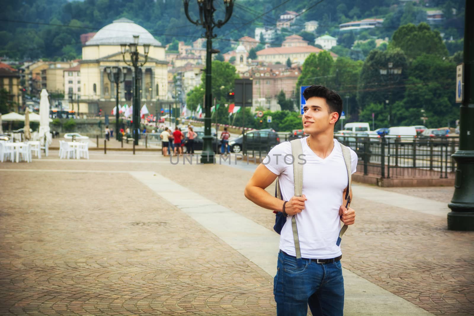 Handsome young man walking in European city square, Piazza Vittorio Veneto in Turin, Italy