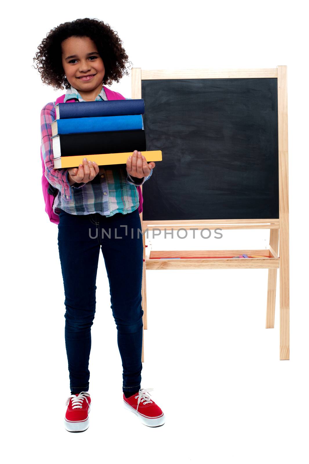 Smiling little girl carrying school books over white