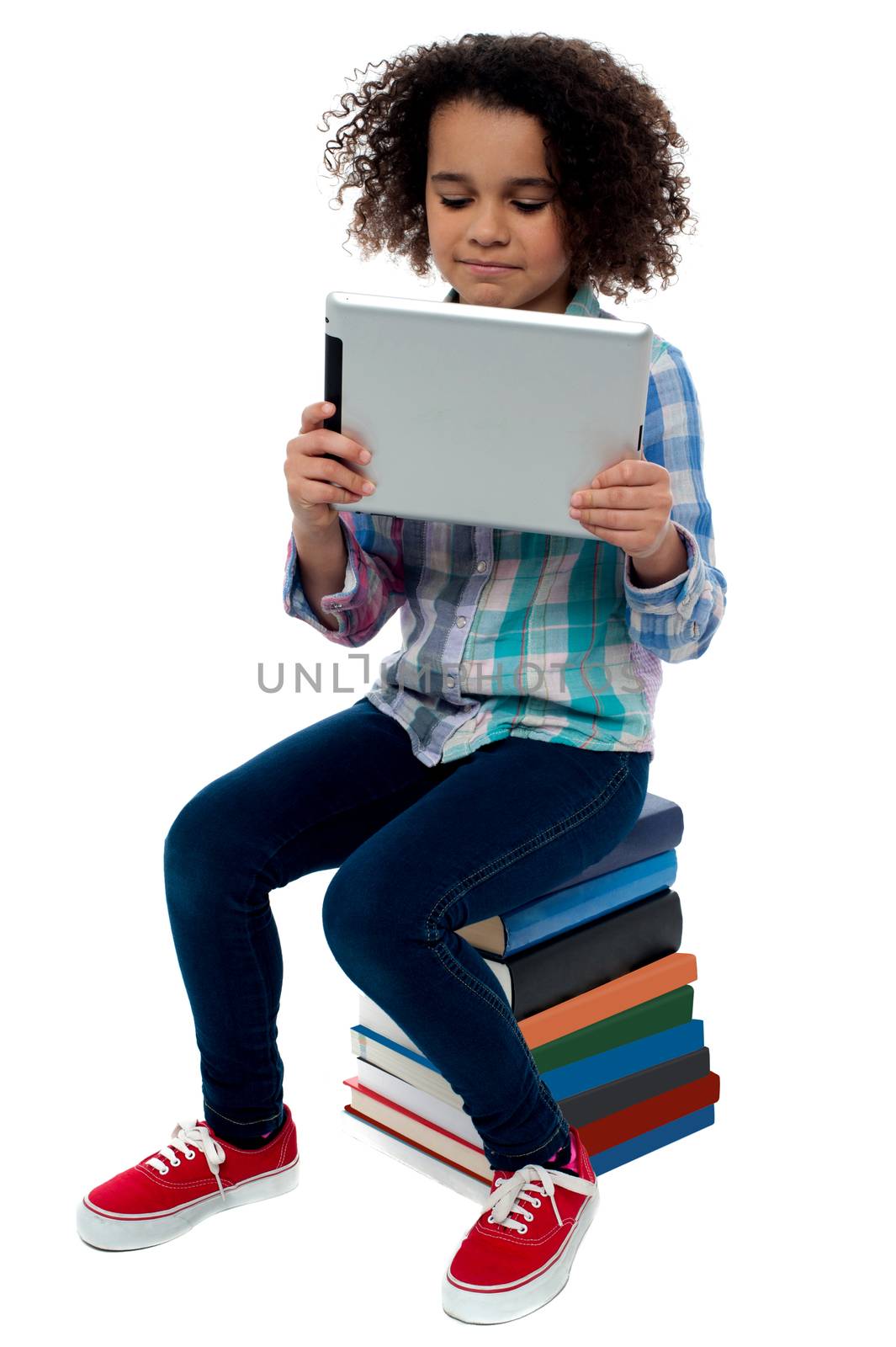 Little girl sitting on books with digital tablet