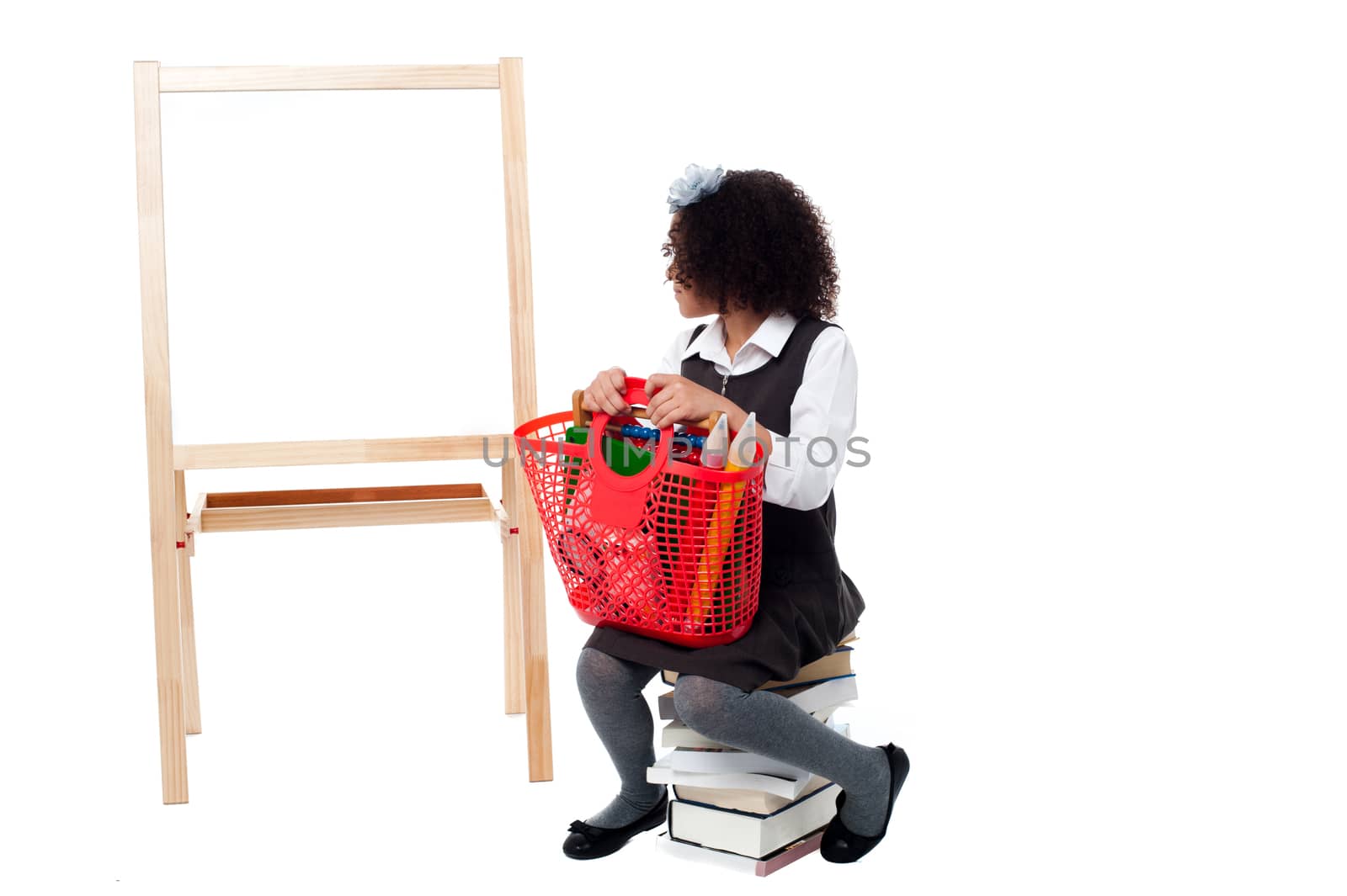 School girl sitting on books, watching the board