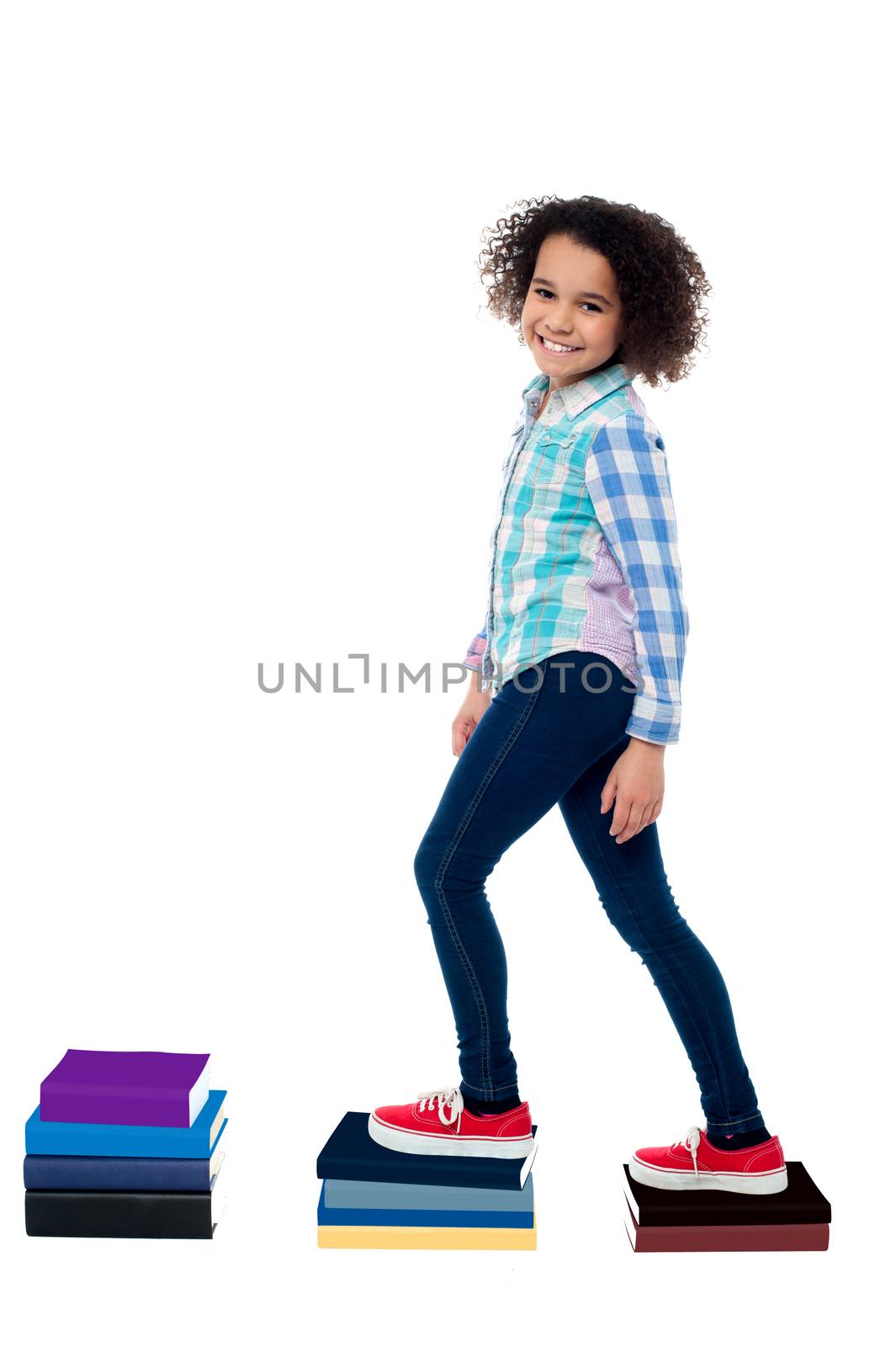 Pretty girl child climbing on notebooks over white