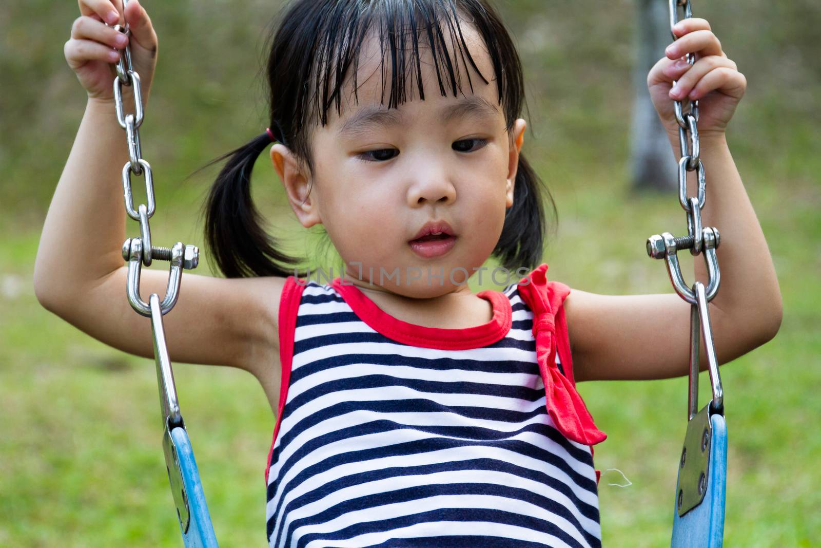 Asian Chinese little girl swing at outdoor park.