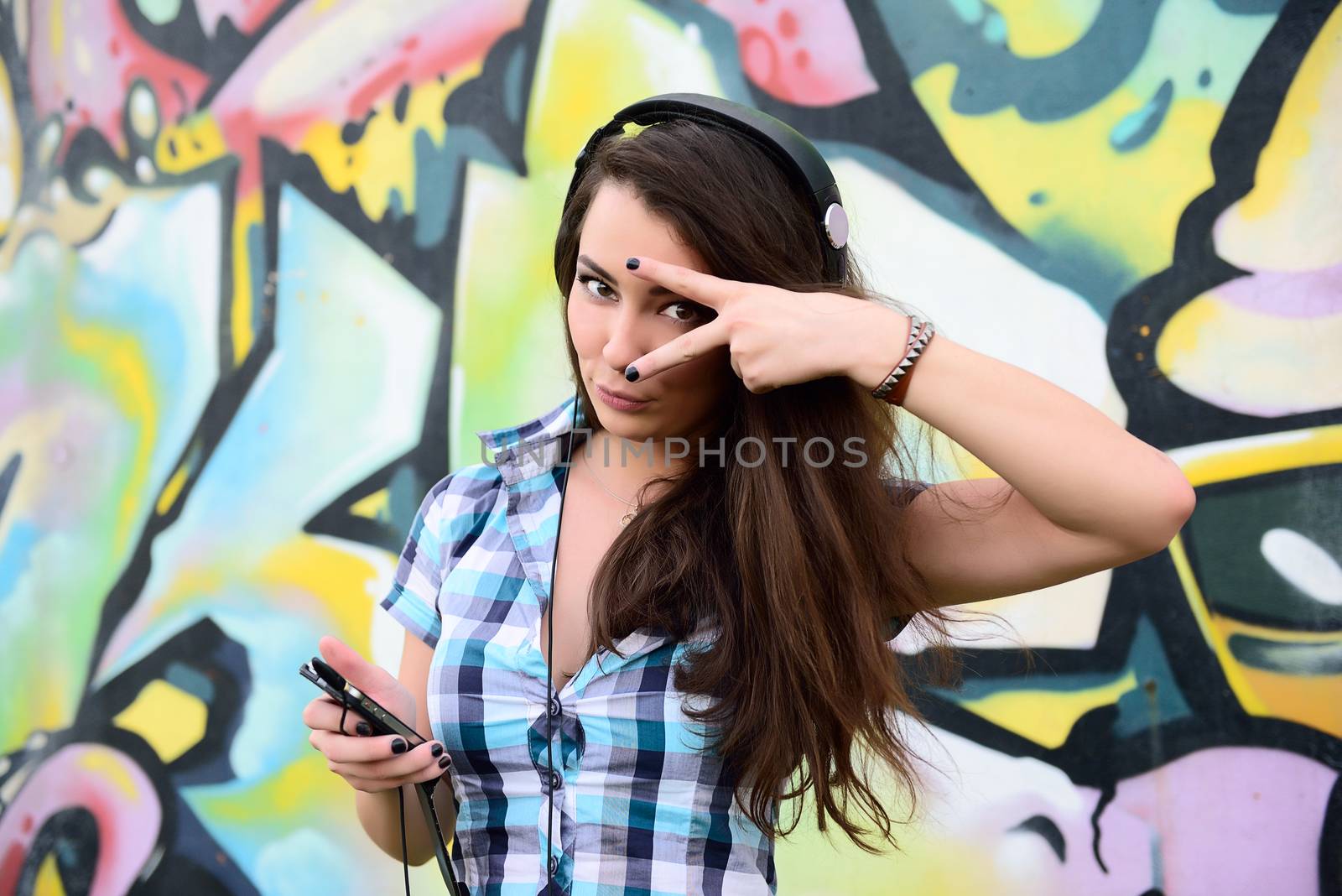 Portrait of young woman sitting at graffiti wall