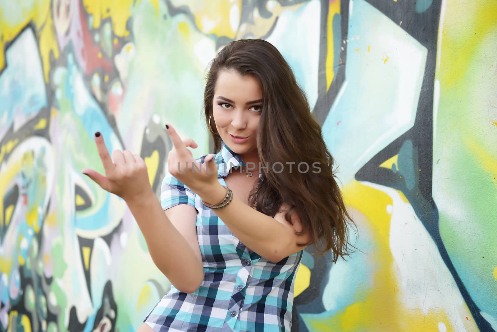 Portrait of young woman sitting at graffiti wall