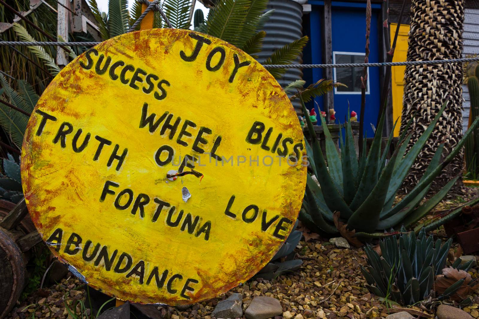 Large round yellow sign with loving messages painted on it with foliage in the background.