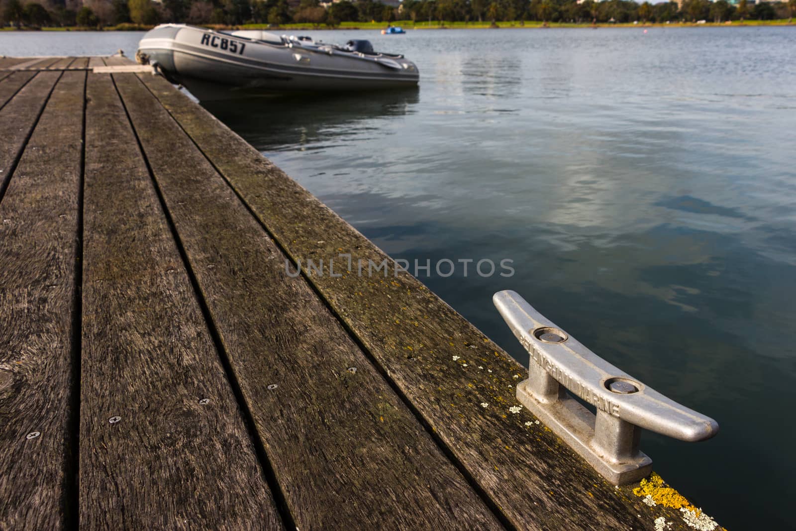 Mooring Bollard with Rubber Dinghy in the Background by davidhewison