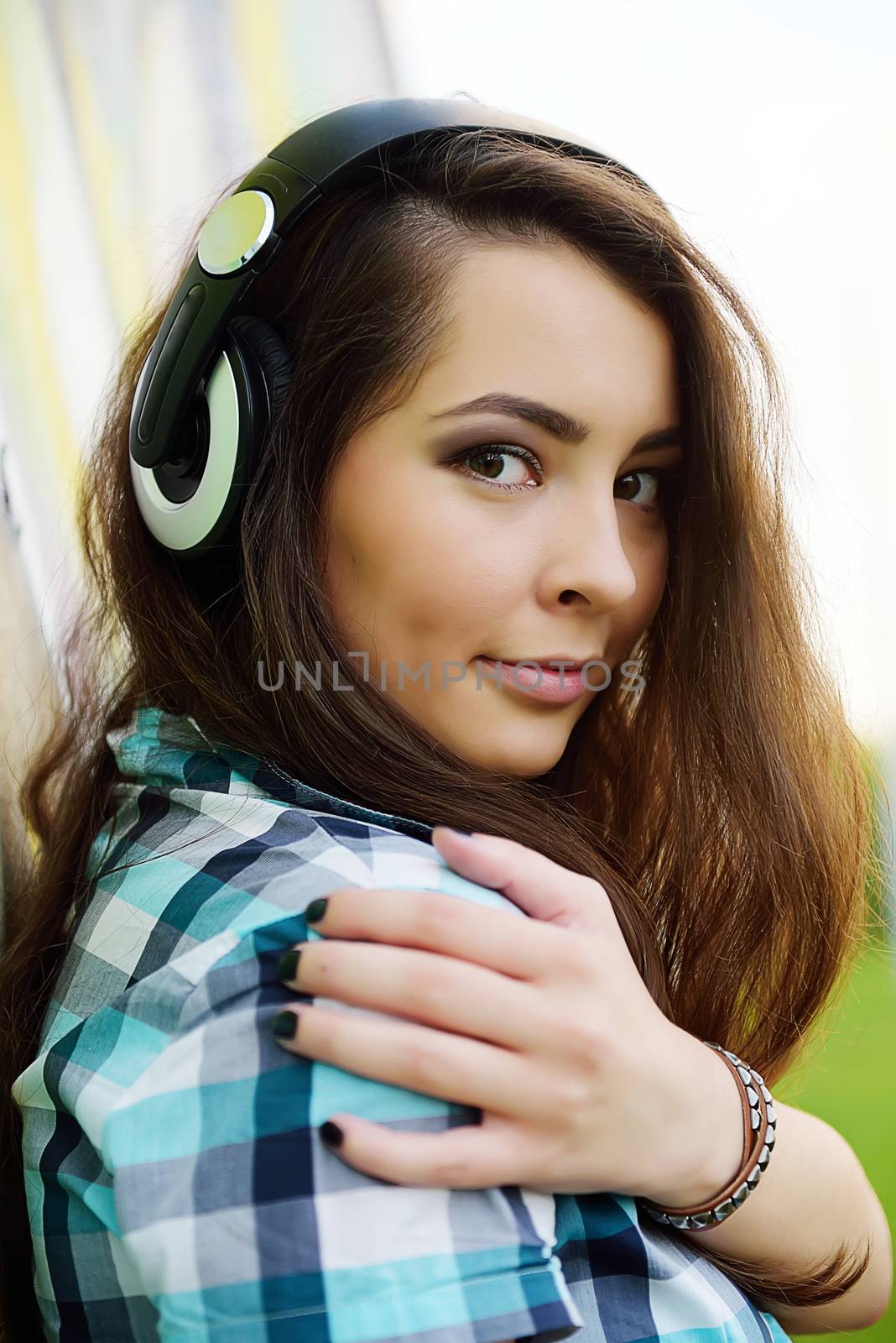  Headphones.Portrait of young woman sitting at graffiti wall