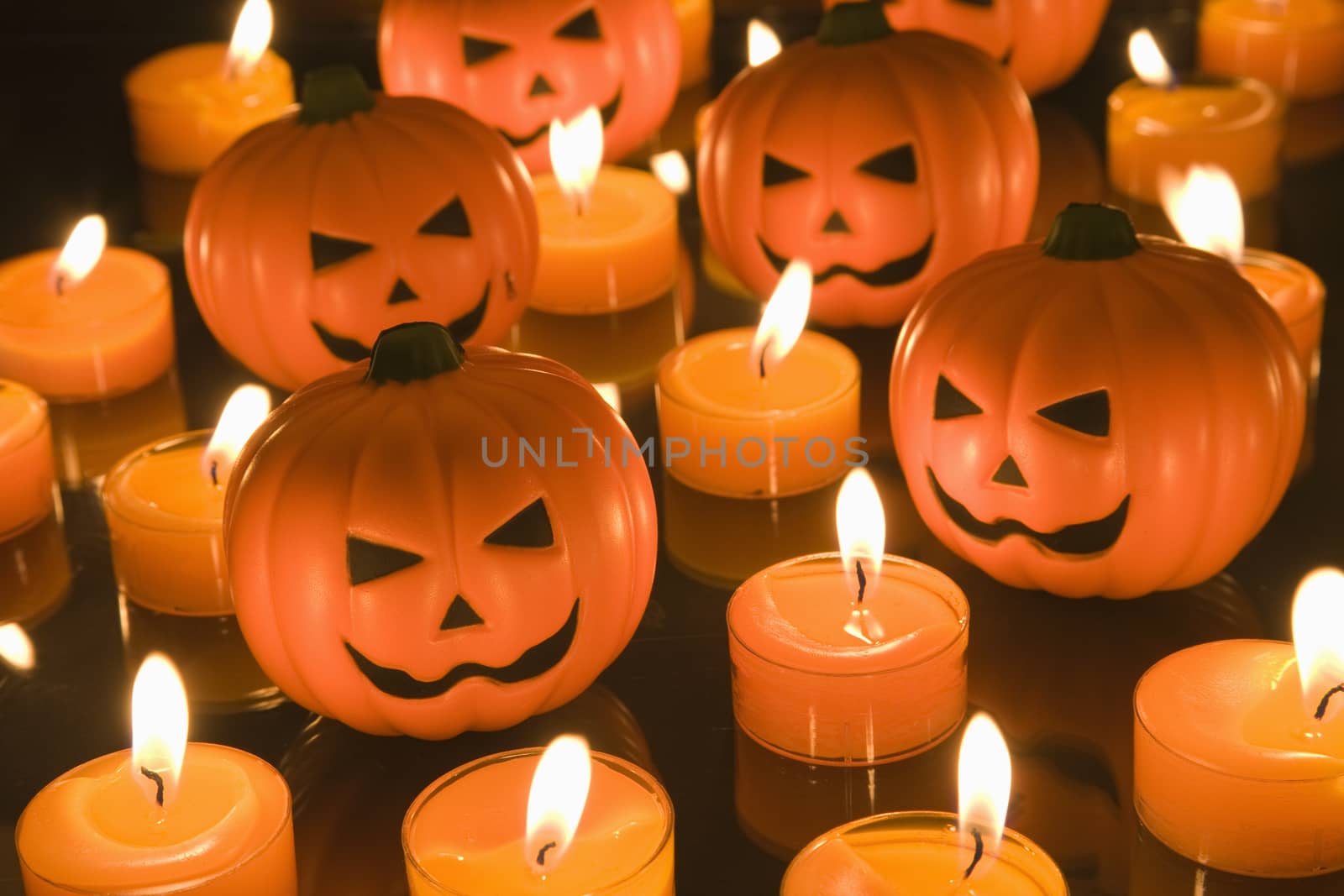 Small Halloween toy Pumpkins surrounded by orange tealight candles