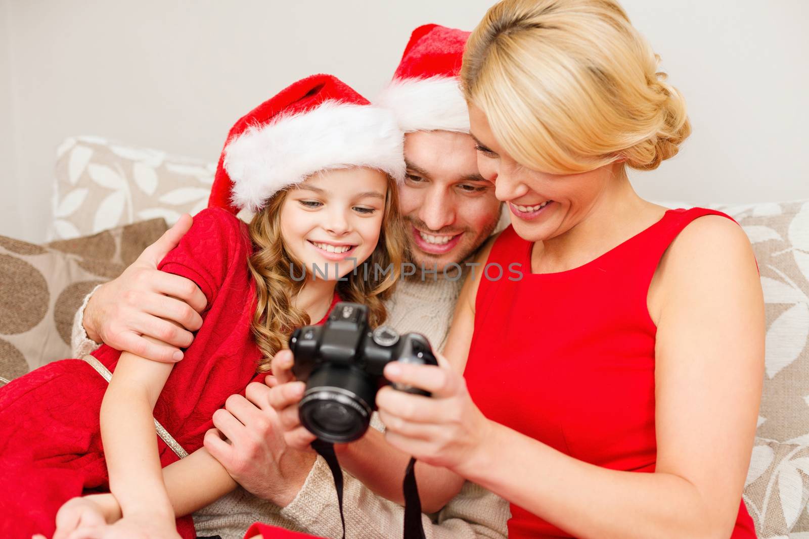 family, christmas, x-mas, happiness and people concept - smiling family in santa helper hats looking at pictures