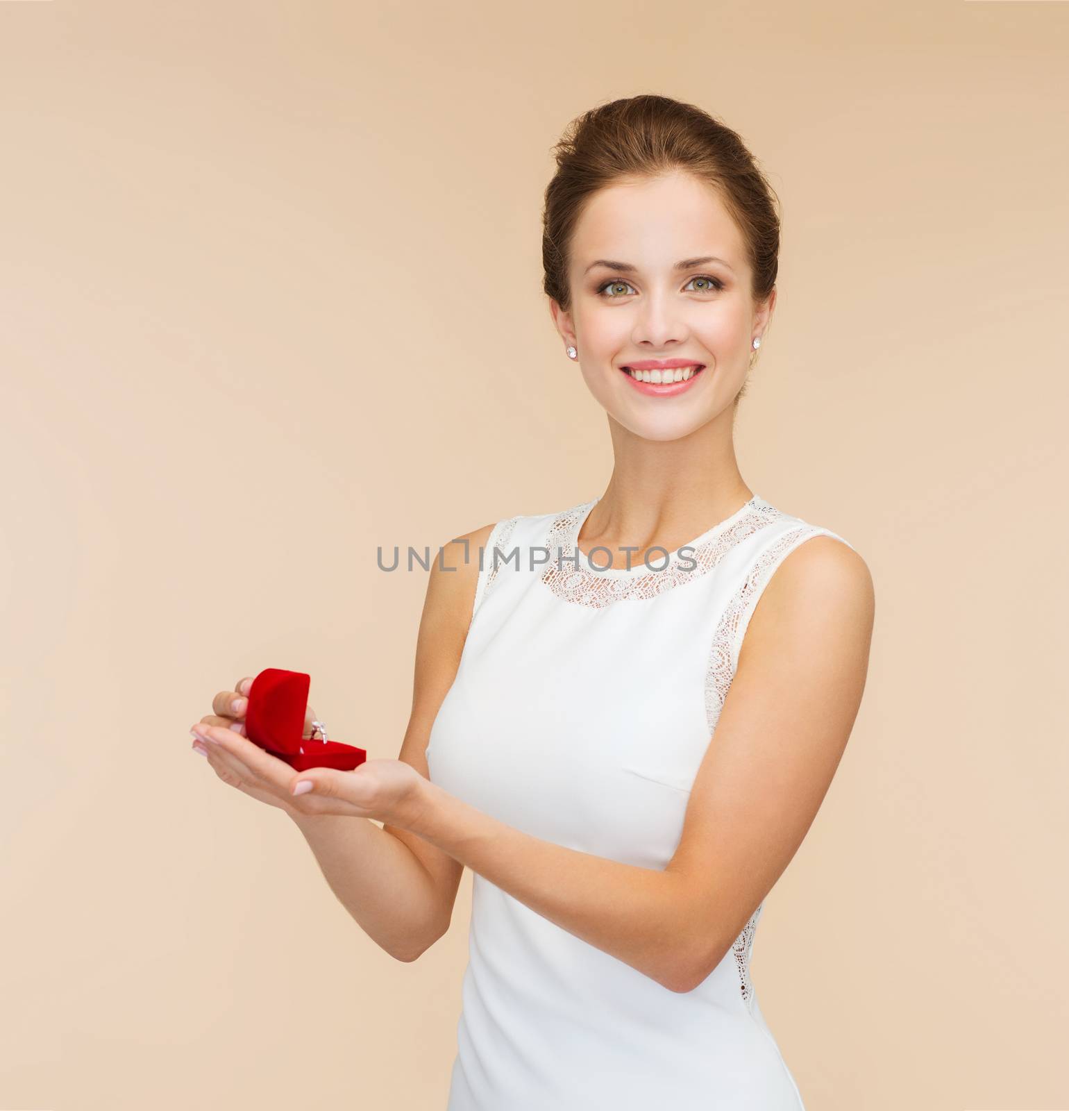 wedding, love, engagement and happiness concept - smiling woman in white dress holding red gift box with diamond ring over beige background