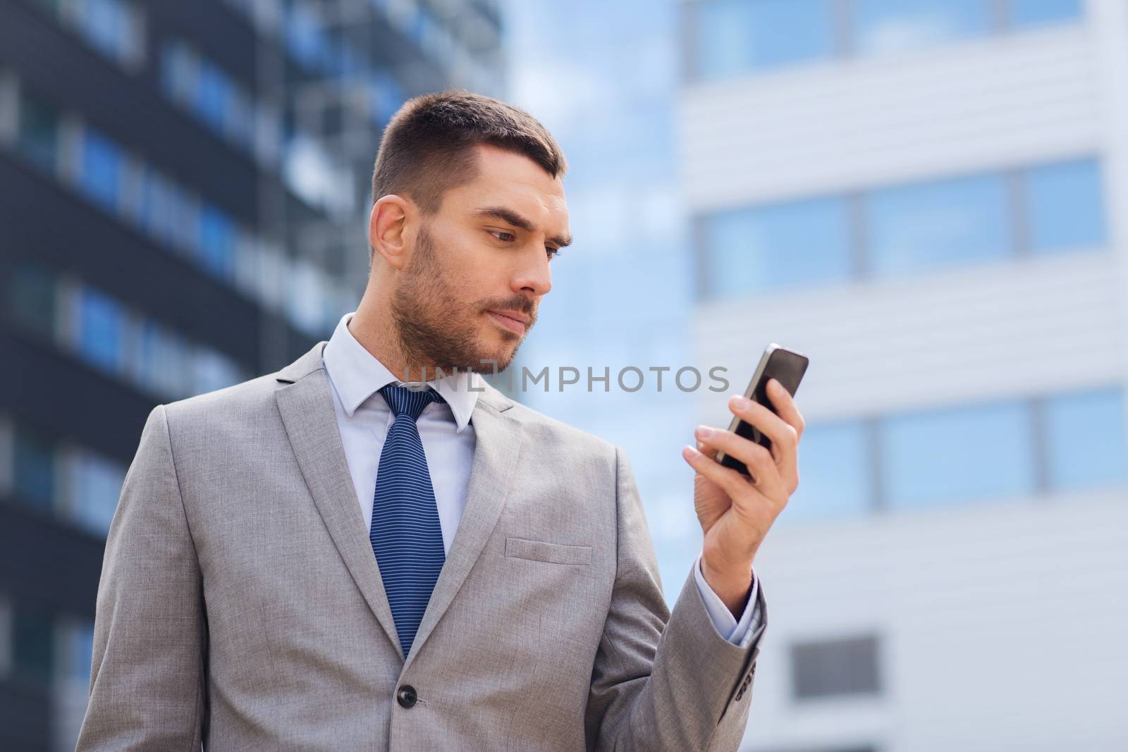 serious businessman with smartphone outdoors by dolgachov
