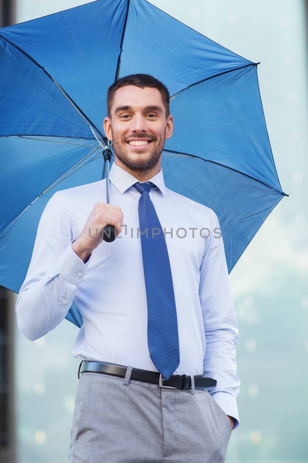 young smiling businessman with umbrella outdoors by dolgachov