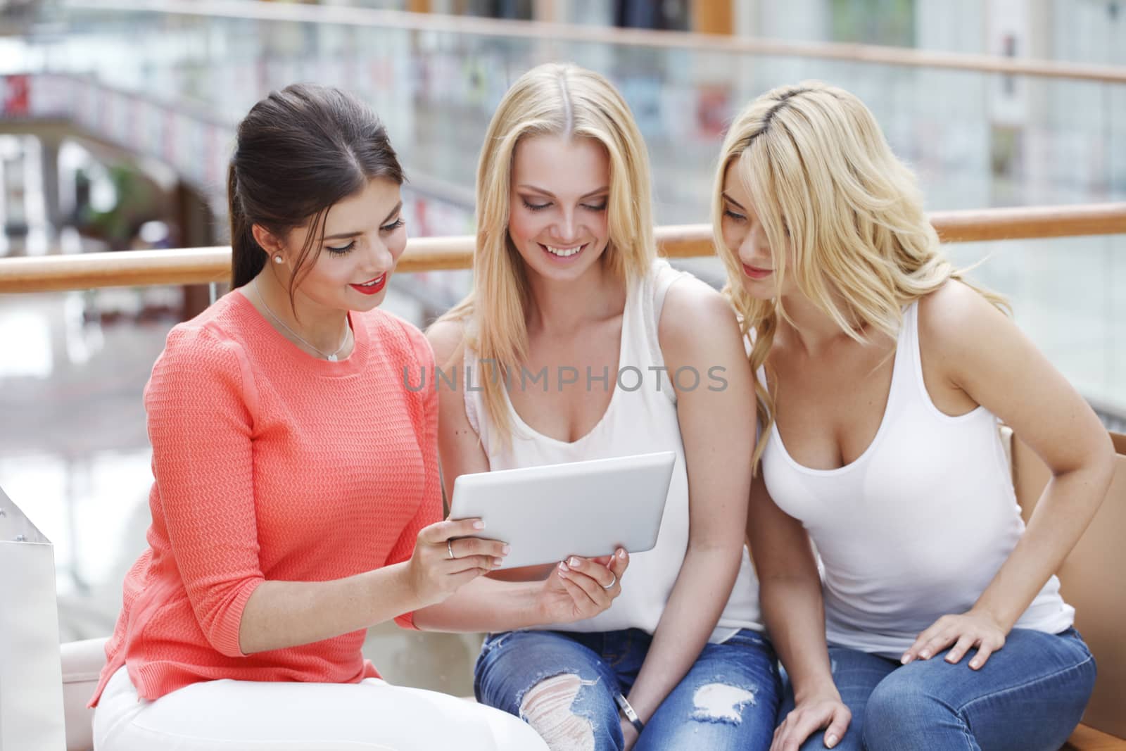 Young beautiful happy women with tablet pc and shopping bags in mall