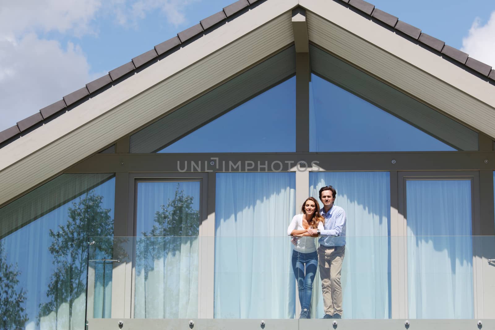 young couple standing on balcony of their house