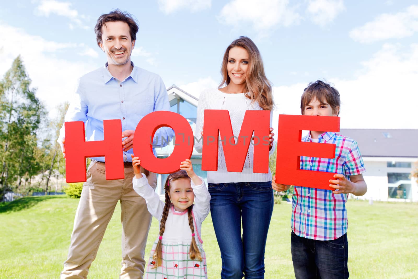 happy holding home letters in front of their house