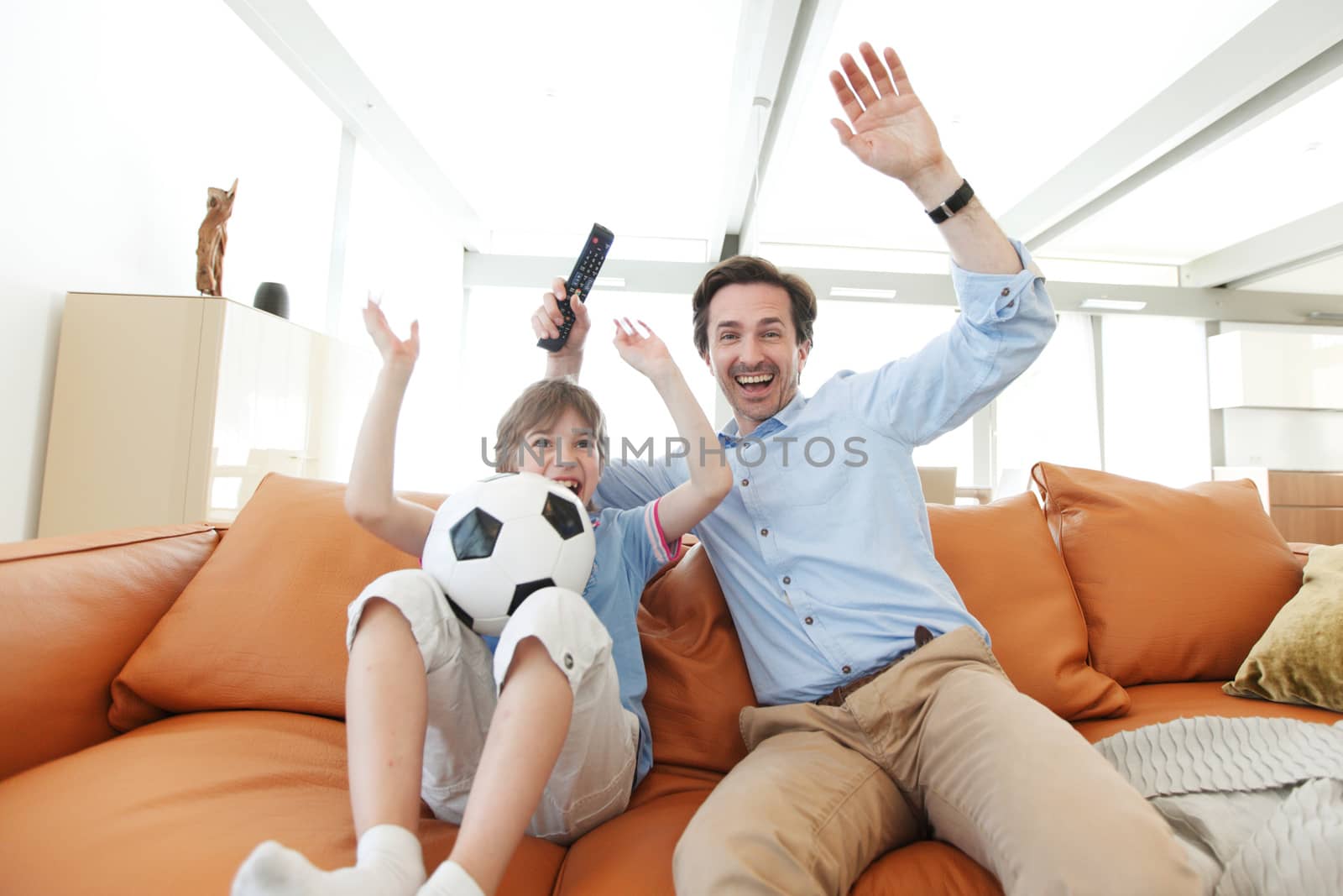 father and son wathcing football inside their house