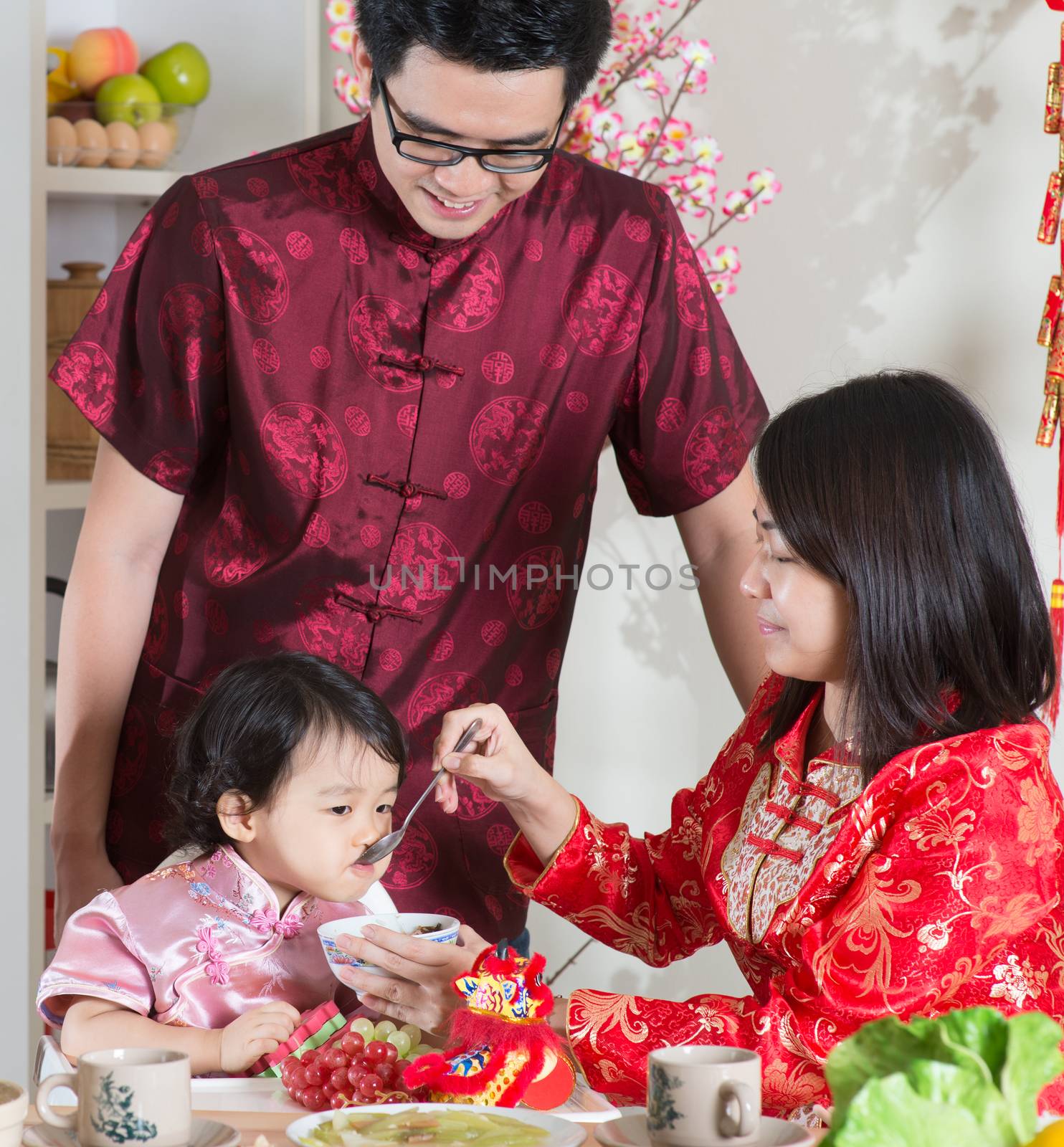 Chinese New Year, reunion dinner. Happy Asian Chinese family with red cheongsam dining at home.